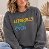 A woman wearing a dark gray crewneck sweatshirt with the text 'LITERALLY CAN'T EVEN' printed on the front in yellow, green, and blue, sitting on a woven chair.