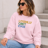 A woman wearing a light pink crewneck sweatshirt with the text 'LITERALLY CAN'T EVEN' printed on the chest in yellow, green, and blue, paired with blue jeans and black sunglasses, sitting on concrete steps.