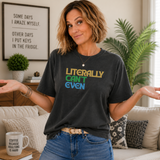A woman wearing a dark charcoal graphic t-shirt with the text 'LITERALLY CAN'T EVEN' in yellow, green, and blue, paired with blue jeans in a cozy living room setting.