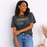 A woman wearing a dark gray graphic t-shirt with the text 'LITERALLY CAN'T EVEN' in yellow, green, and blue, paired with blue jeans, standing against a white wall.