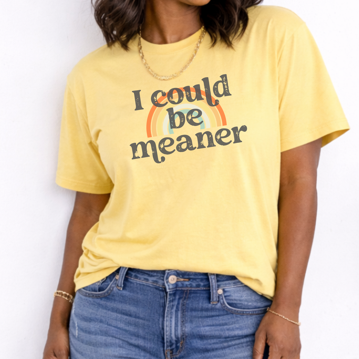 Person wearing a yellow t-shirt with a rainbow and text design against a white background