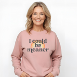 Woman wearing a pink sweatshirt with 'I could be meaner' text and rainbow design on a white background