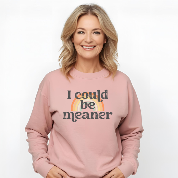 Woman wearing a pink sweatshirt with 'I could be meaner' text and rainbow design on a white background