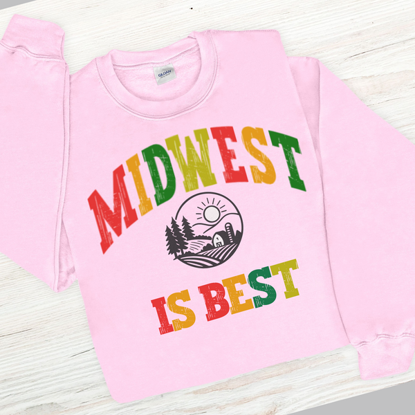 Pink sweatshirt with 'Midwest is Best' text in colorful letters on a wooden surface