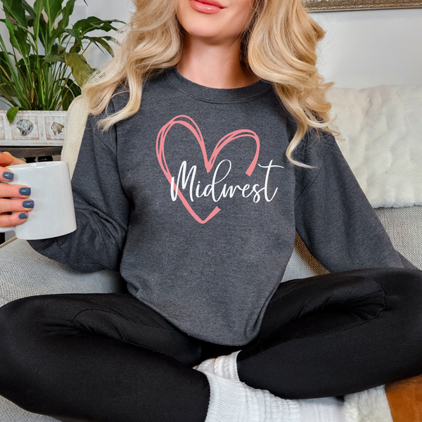 Person wearing a gray sweatshirt with 'Midwest' and a heart design, holding a mug.