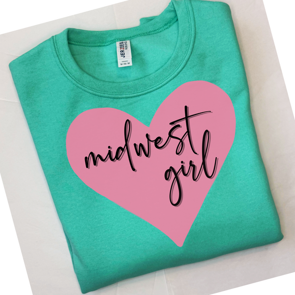 Folded mint green t-shirt with pink heart and 'midwest girl' text on a white surface