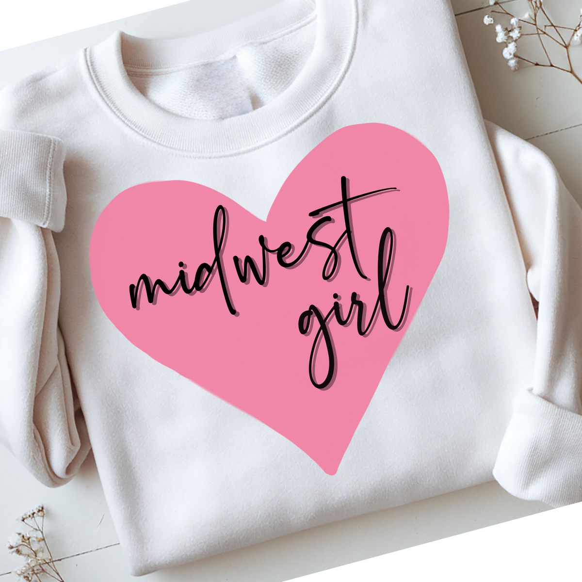 White sweatshirt with a pink heart and 'midwest girl' text on a light background