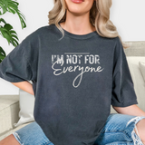 Person wearing a faded black t-shirt with 'I'm not for everyone' text, sitting on a couch.