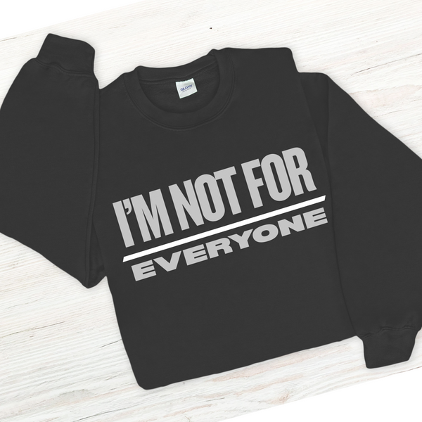 Black sweatshirt with 'I'm not for everyone' text on a white wooden surface