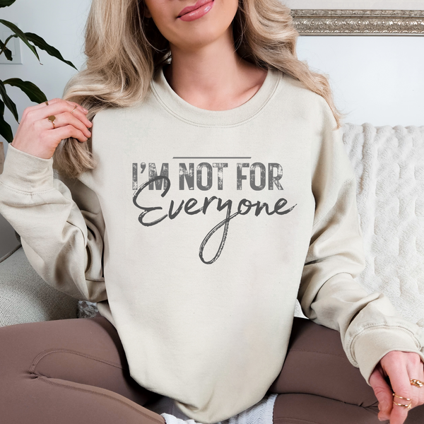 Person wearing a beige sweatshirt with text sitting on a couch.