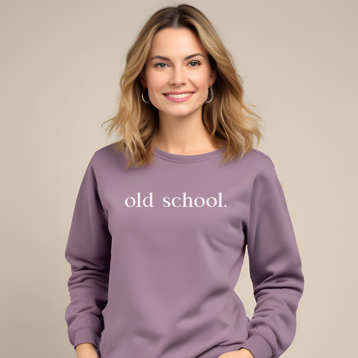 Woman wearing a paragon purple sweatshirt with 'old school.' text on a beige background