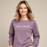 Woman wearing a paragon purple sweatshirt with 'old school.' text on a beige background