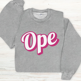 Gray sweatshirt with 'Ope' text in pink and white on a light wooden surface