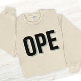 Beige sweatshirt with 'OPE' printed on it laid flat on a wooden surface