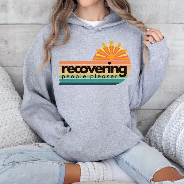 Person wearing a gray hoodie with a colorful graphic and text on a wooden background