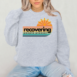 Person wearing a gray sweatshirt with a colorful graphic and text on a plain background