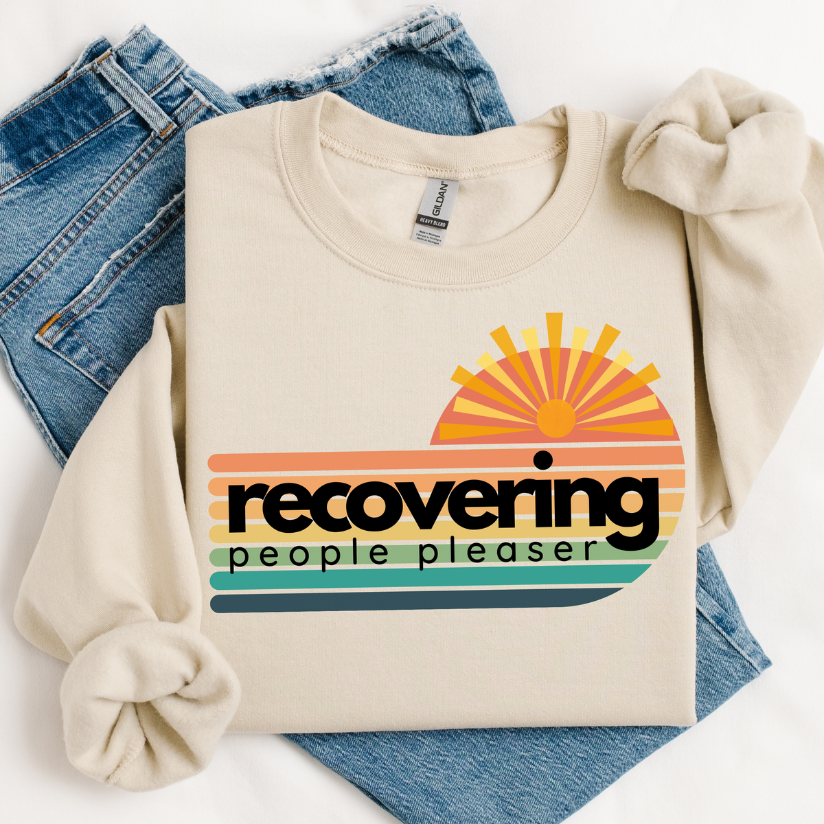 Beige sweatshirt with colorful graphic and text 'recovering people pleaser' on a white background.