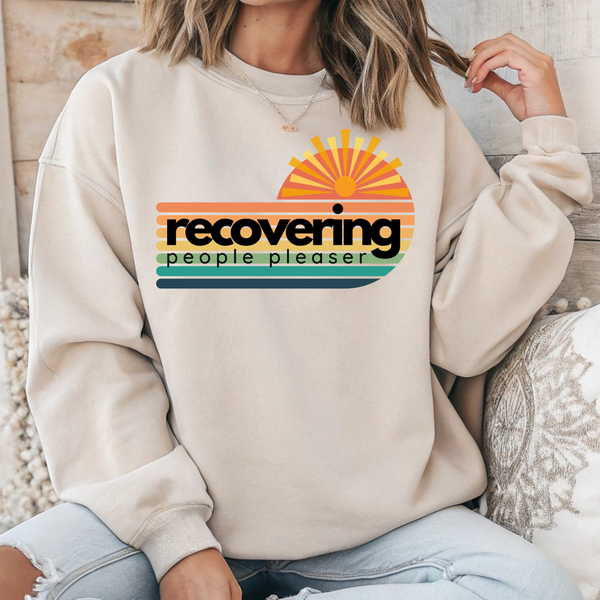 Person wearing a beige sweatshirt with a colorful graphic and text.