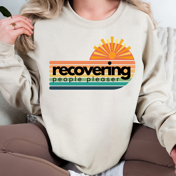Person wearing a beige sweatshirt with a colorful graphic and text.