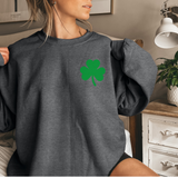 A woman wearing a dark gray sweatshirt with a small pocket-sized shamrock on the top left of the sweatshirt.