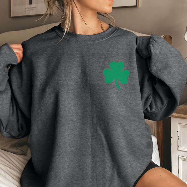 Person wearing a gray sweatshirt with a green shamrock design.