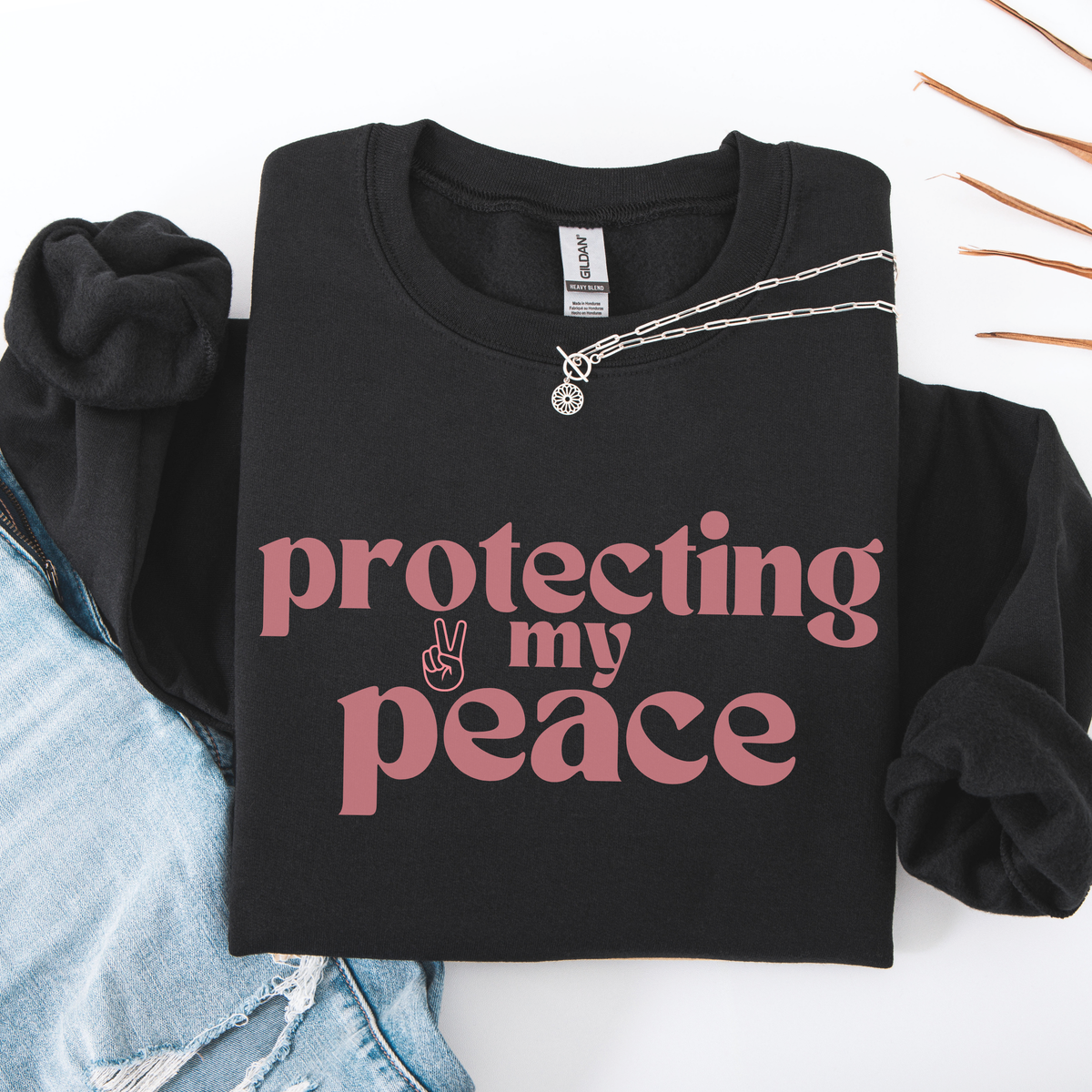 Black sweatshirt with 'protecting my peace' text in pink on a white background