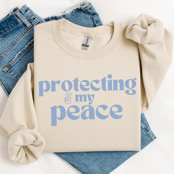 Beige sweatshirt with 'protecting my peace' text on a white background