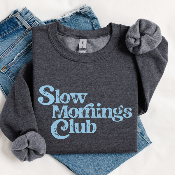 Dark Gray sweatshirt with 'Slow Mornings Club' blue text on folded jeans