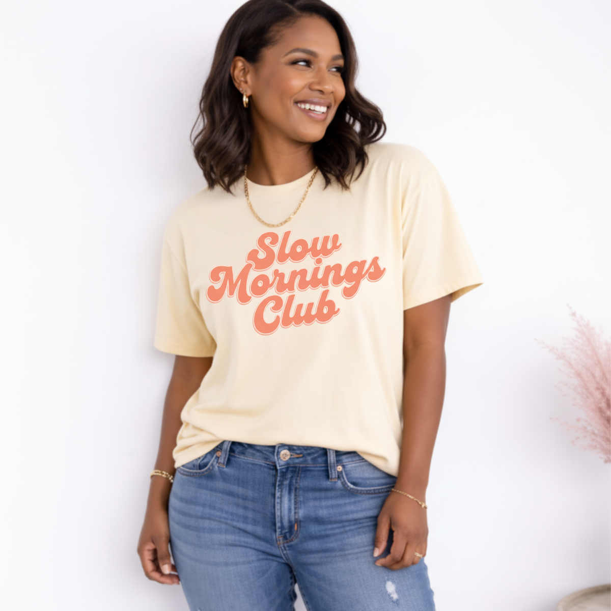 Woman wearing a 'Slow mornings Club' t-shirt against a white background