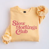 Yellow sweatshirt with 'Slow Mornings Club' pink text on a white background