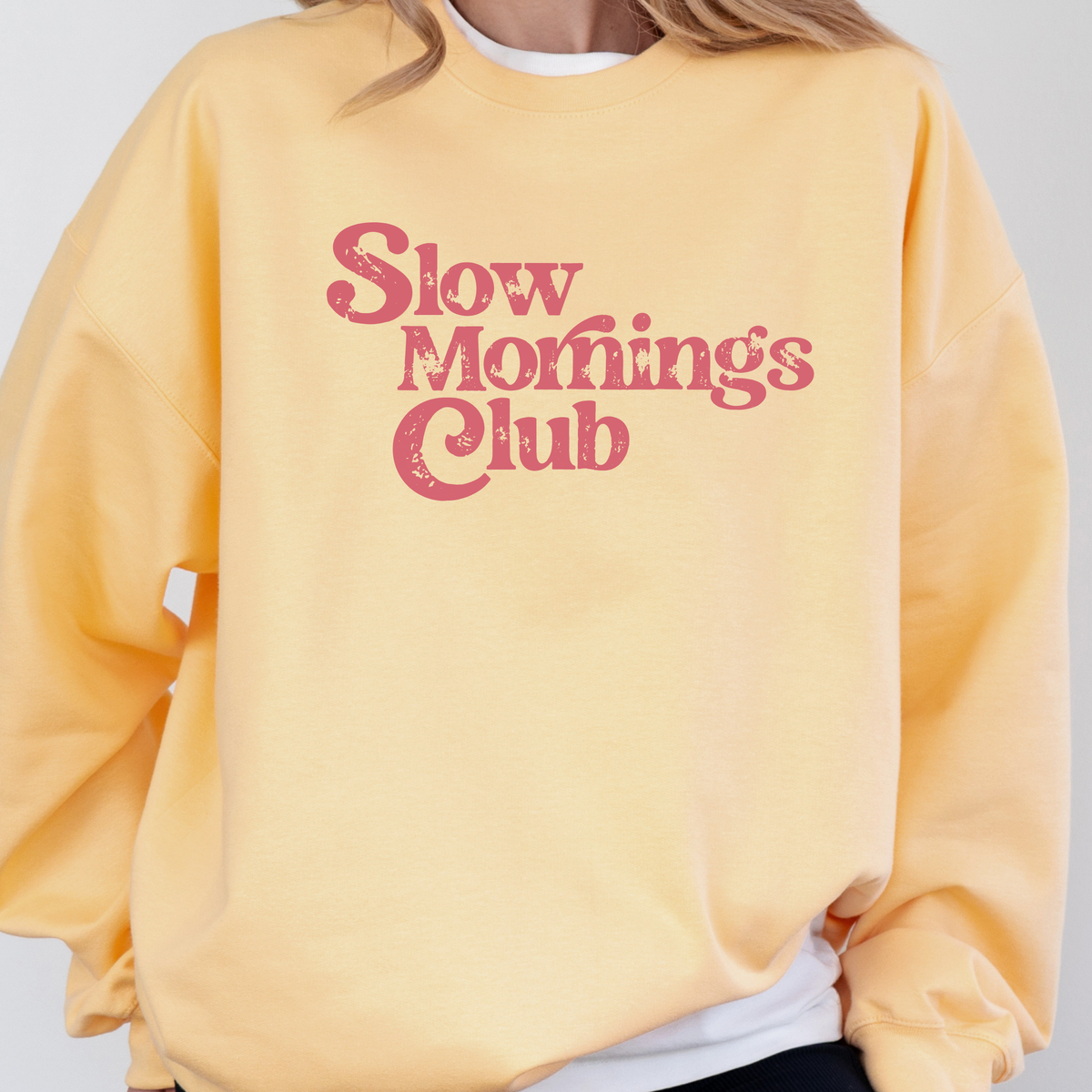 Yellow sweatshirt with 'Slow Morning's Club' text on a plain background