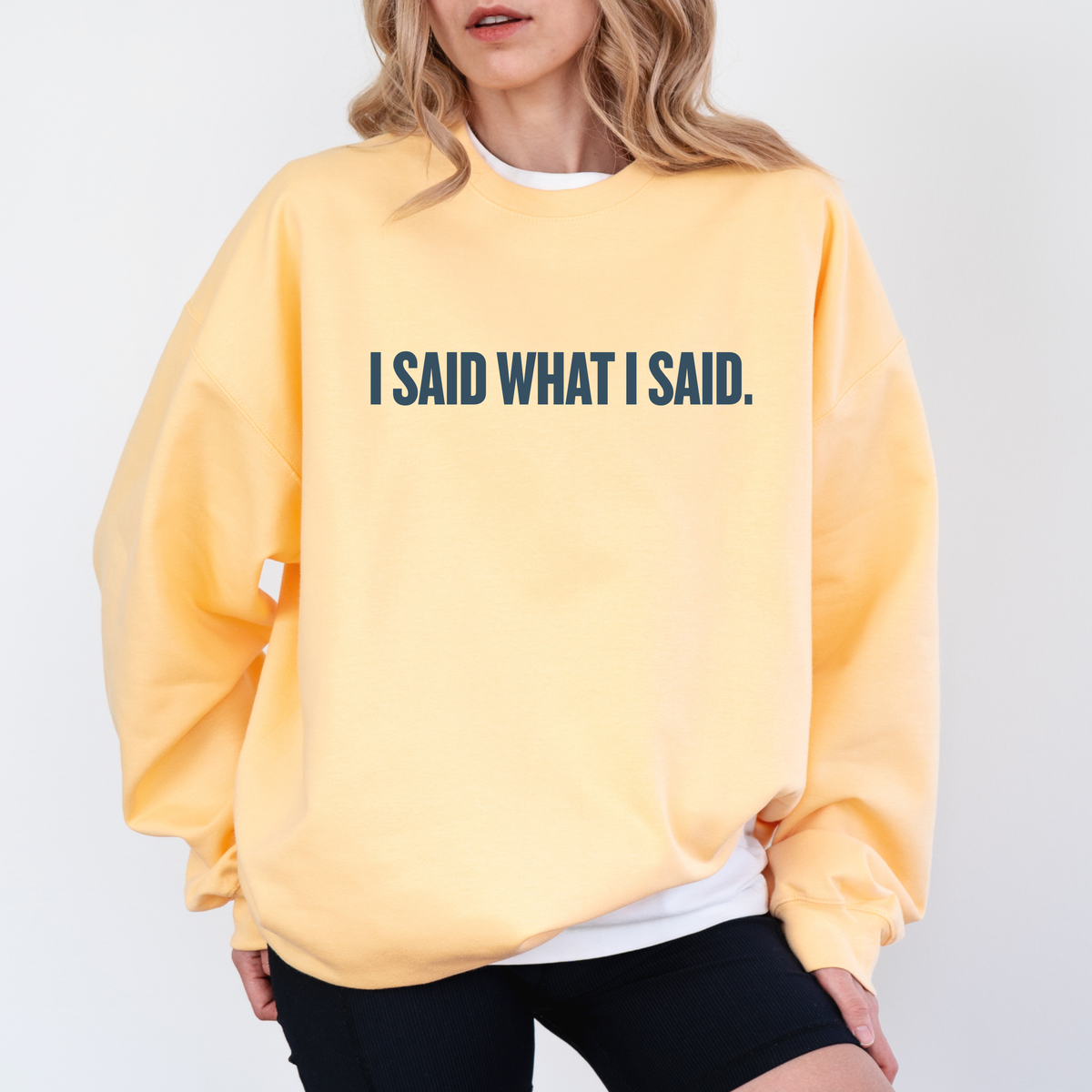 A woman in a yellow sweatshirt with 'I SAID WHAT I SAID.' text 
