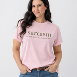 Woman wearing a pink t-shirt with 'sarcasm is my love language' text on a light gray background