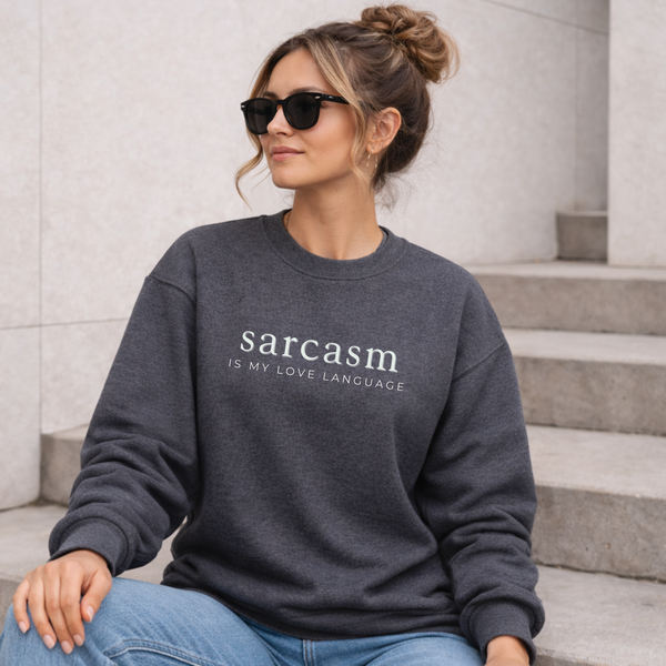 Woman wearing a sweatshirt with 'sarcasm is my love language' text, sitting on steps.
