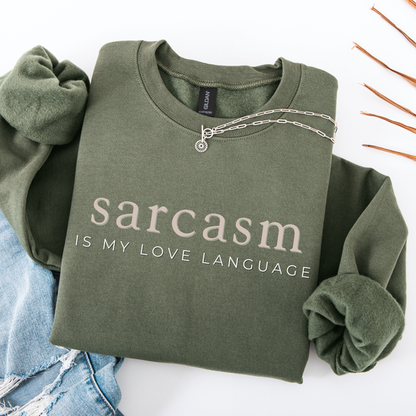 Green folded sweatshirt with 'sarcasm is my love language' text on a white background