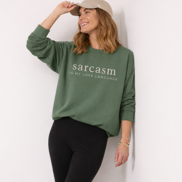 Woman wearing a green sweatshirt with 'sarcasm is my love language' text against a white background