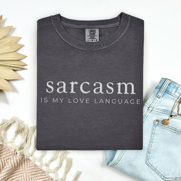 Dark gray t-shirt with 'sarcasm is my love language' text on a light background