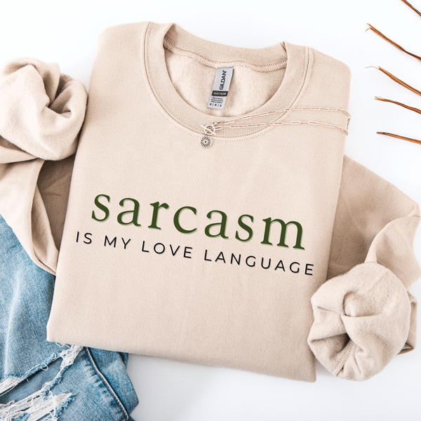 Beige sweatshirt with 'sarcasm is my love language' text on a white background