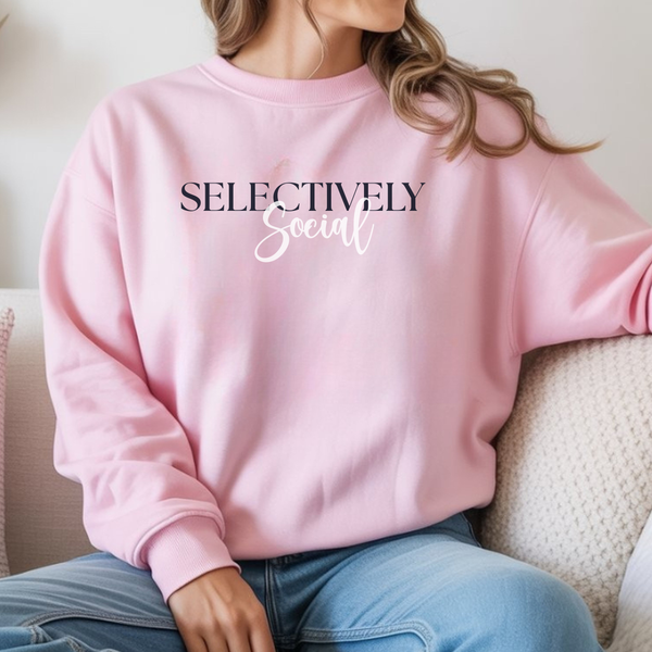 Person wearing a pink sweatshirt with 'SELECTIVELY Social' text, sitting on a couch.