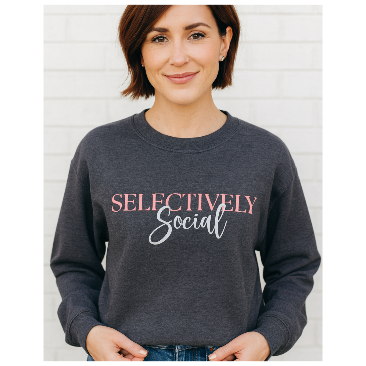Middle age woman in a dark gray sweatshirt with the words "Selectively Social" written in pink and white font.