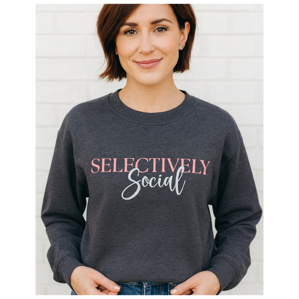 Middle age woman in a dark gray sweatshirt with the words "Selectively Social" written in pink and white font.