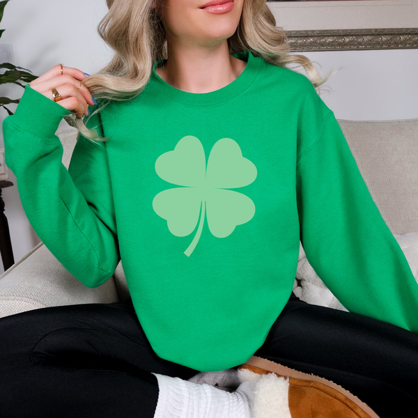 Person wearing a green sweatshirt with a shamrock design indoors.