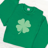 A green sweatshirt with a large lighter green shamrock in the middle.