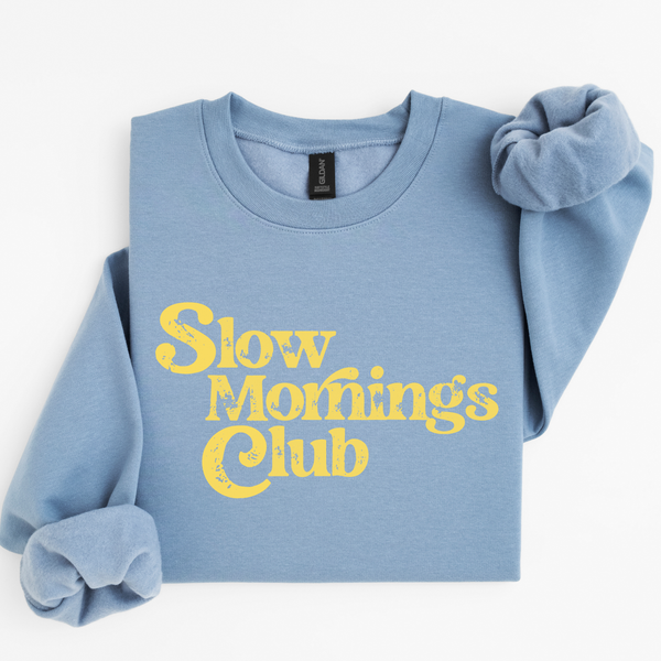 Blue sweatshirt with yellow text 'Slow Mornings Club' on a white background