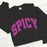 Black sweatshirt with pink 'SPICY' text on a light wooden surface