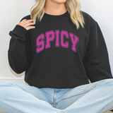 Person wearing a black sweatshirt with 'SPICY' in pink text, sitting on a white background.