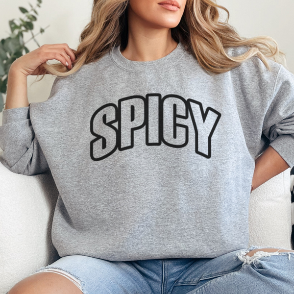 Person wearing a gray sweatshirt with 'SPICY' text, sitting on a white couch.