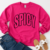 A bright pink crewneck sweatshirt with the word 'SPICY' printed across the chest in bold black-outlined pink letters, styled in a flat lay with blue jeans and white slide sandals on a white background.