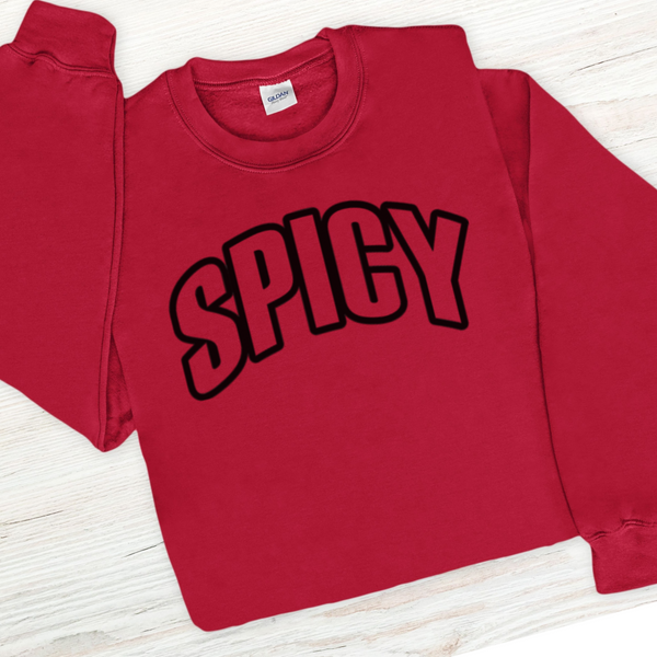 Red sweatshirt with 'SPICY' text on a light wooden surface
