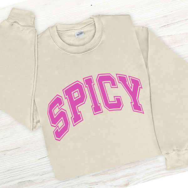 Beige sweatshirt with 'SPICY' in pink text on a wooden surface